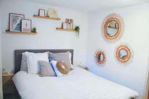 a bedroom with a white bed with pillows and mirrors at Sotto Terra in Katwijk aan Zee