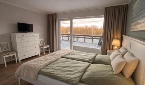 a bedroom with a large bed and a balcony at Golfresidenz Landidyll B 107 in Grömitz
