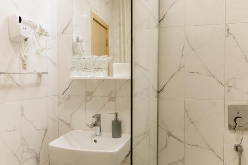 a white bathroom with a sink and a shower at Hotel N in Belgrade