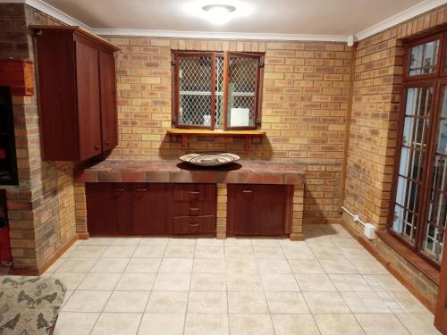a kitchen with wooden cabinets and a brick wall at The Victorian Villa in Chintsa