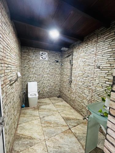 a bathroom with a toilet and a stone wall at 22 apartments in Kalapaluwawa