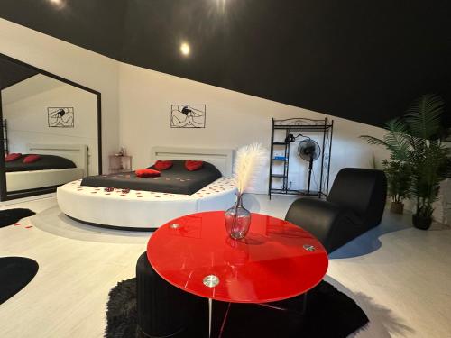 a room with two beds and a red table at Love Room La Crèche Romantique in Bogny Sur Meuse
