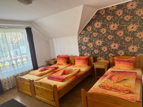 a bedroom with two beds and a wall with flowers at Casa Flamingo in Sovata