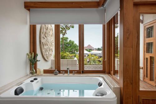 a bath tub in a room with a window at Harsono Boutique Resort Bali in Sanur
