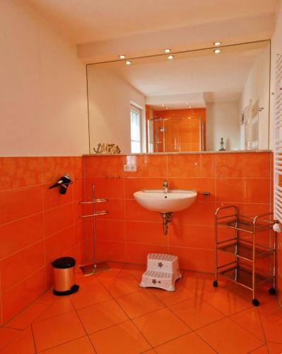 an orange bathroom with a sink and a mirror at Strandstr_ in Zingst