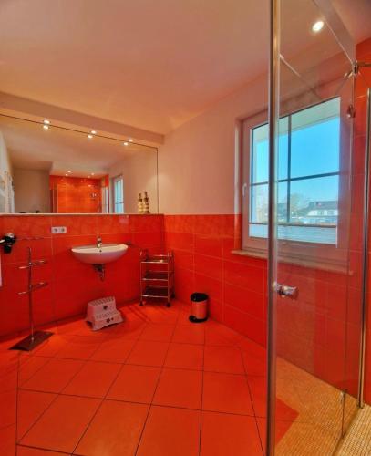 a red tiled bathroom with a sink and a shower at Strandstr_ in Zingst