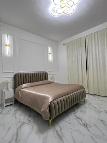 a large bed in a white room with a chandelier at Luxury Rooms K91 in Foggia