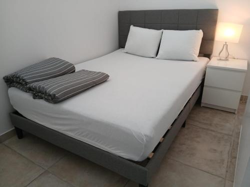 un letto con lenzuola e cuscini bianchi in una camera da letto di Cloche d'or a Lussemburgo