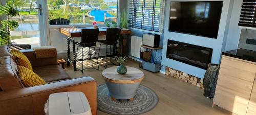 a living room with a couch and a television and a table at Poellodge, Luxe houseboot met zonnig terras in Aalsmeer