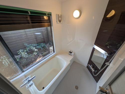 a bathroom with a tub and a window and a sink at N Yamanakako Club in Yamanakako