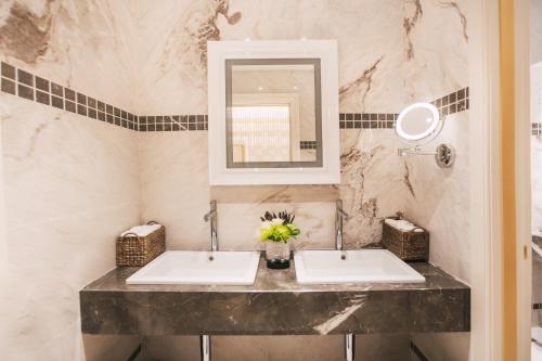 a bathroom with two sinks and a mirror at The Biltmore Tbilisi Hotel in Tbilisi City