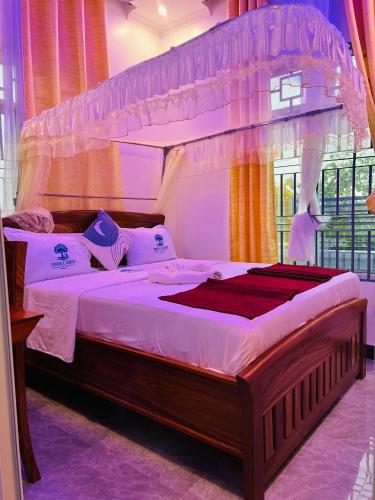 a bedroom with a large bed with a canopy at Triple E Lodge Kibaha in Kibaha
