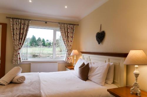 a bedroom with a white bed and a window at Roxby a stunning bungalow on the banks of the river within a 2 minute walk of Lake Ullswater and Pooley Bridge in Pooley Bridge