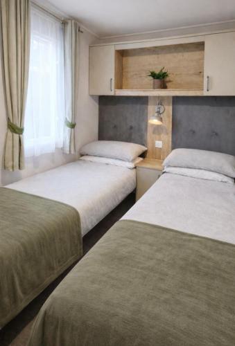 two beds in a small room with a window at Cheviot Pines Northumberland in Swarland