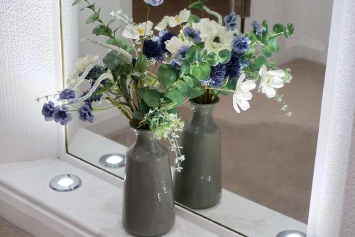 two vases with flowers sitting on a mirror at Roxby a stunning bungalow on the banks of the river within a 2 minute walk of Lake Ullswater and Pooley Bridge in Pooley Bridge