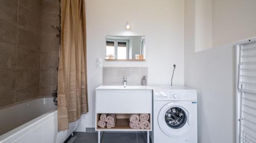 a bathroom with a sink and a washing machine at Au petit détour Confort in Rolampont