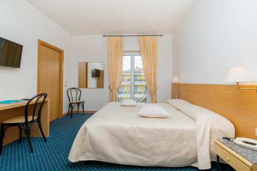 a hotel room with a bed and a desk at Albergo Al Caminetto in Nago-Torbole