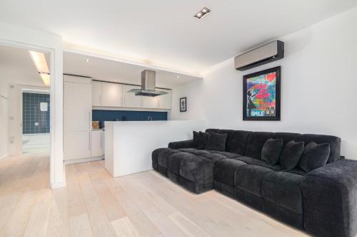 a living room with a black couch and a kitchen at City of London 2BR Penthouse with Stunning Terrace View & Air Condition in London