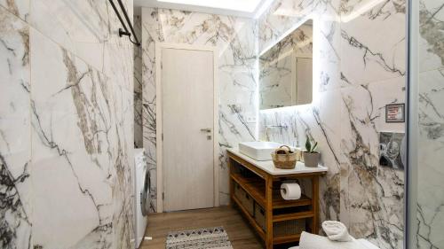 a bathroom with marble walls and a sink and a mirror at Villa Filothea with Jacuzzi & SV by CorfuEscapes in Spartýlas