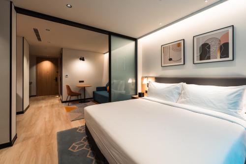 a bedroom with a large bed and a living room at Alt Life Stays - Manyata Tech Park in Bangalore