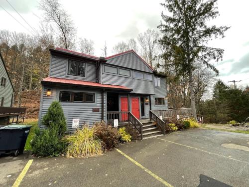 a gray house with a red door in a parking lot at Mountain bike Ski Eville Mecca in Ellicottville