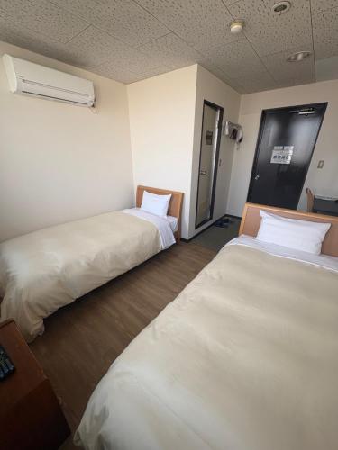 two beds in a hotel room with white sheets at ホテル土浦神立ヒルズ in Tsuchiura
