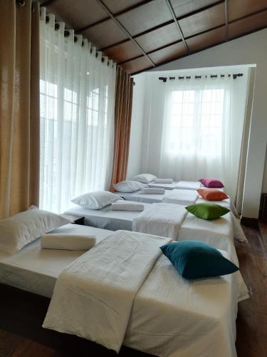 a row of beds in a room with windows at Star Gate Hostel in Nuwara Eliya