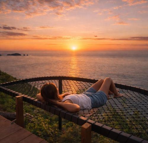 a woman laying on a bench watching the sunset at Eco-tourist Dream Beach Cliff Villas in Nusa Penida