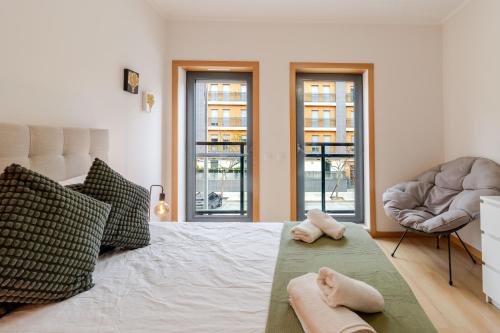 a bedroom with a bed and a chair and windows at HolidaysPT 1 - Marina Village 2 bedroom apartment in Olhão