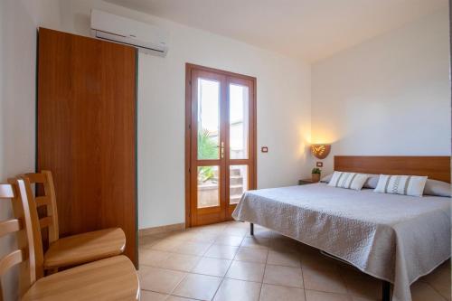 a bedroom with a bed and a window and a chair at Verande Tanca Torre in Isola Rossa
