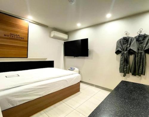 a room with a bed and a flat screen tv at Motel Some in Suwon