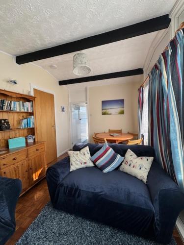 a living room with a blue couch and a table at Caban Caru 2 in Tywyn