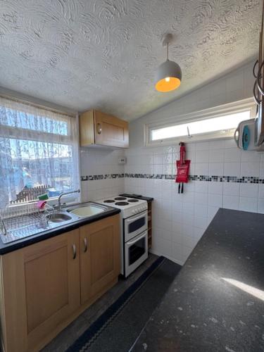 a kitchen with a stove and a sink and a window at Caban Caru 2 in Tywyn