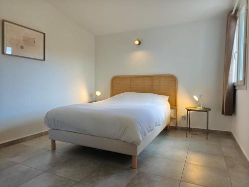a bedroom with a large bed with white sheets at Valduccina - T3 avec terrasse et piscine, proche de la plage in Lecci