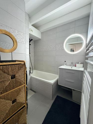 a bathroom with a tub and a sink and a mirror at Les Embruns de Tarnos in Tarnos