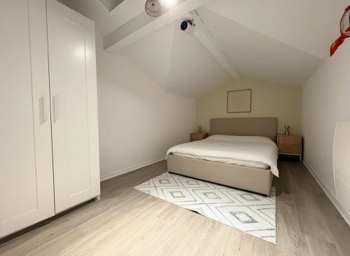 a white bedroom with a bed and a rug at Les Embruns de Tarnos in Tarnos