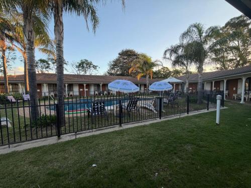 two blue umbrellas on a fence next to a pool at CAPRICORN MOTOR inn in Mulwala