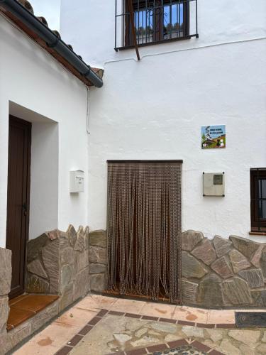 a white building with a gate and a stone wall at El callejón in Benarrabá