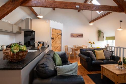 a kitchen and living room with leather couches and a table at Bryn Lon Bach in Caeʼr-geiliog