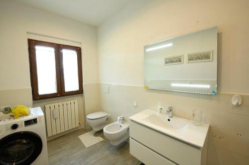a white bathroom with a sink and a toilet at Il loggiato del chianti in Cavriglia