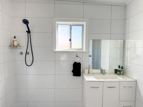 a white bathroom with a sink and a shower at Saltbush Cottage in Broken Hill
