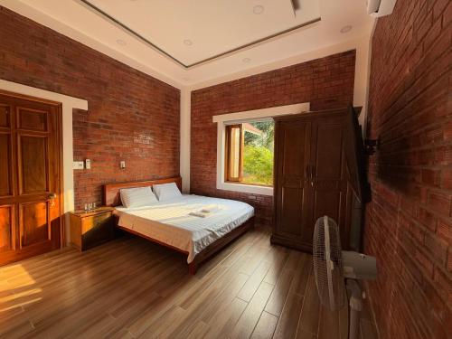 a bedroom with a bed and a brick wall at vuyen villa in Phú Quốc