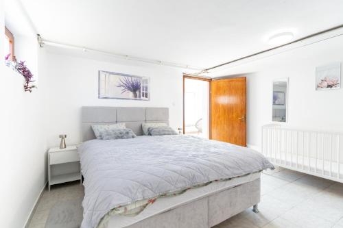 a white bedroom with a large bed and a window at Apartman Suman in Vukovar