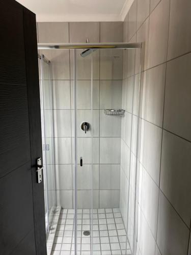 a shower with a glass door in a bathroom at The Arrose Guest House in Kwamhlanga