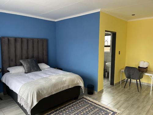 a bedroom with a blue wall and a bed at The Arrose Guest House in Kwamhlanga