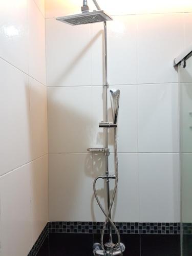 a shower in a bathroom with a white tiled wall at ChaoPingJia Fengge Guesthouse in Wujie