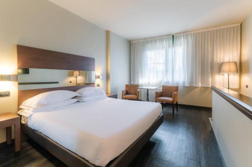 a hotel room with a large white bed and chairs at Smart Hotel King, by R Collection Hotels in Varedo