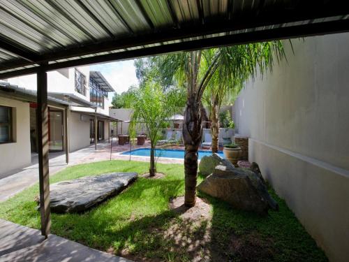 a courtyard with a palm tree and a swimming pool at Monte Bello Guesthouse in Windhoek