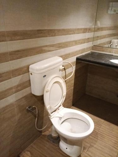 a bathroom with a white toilet in a room at Hotel HV Palace in Bhuj
