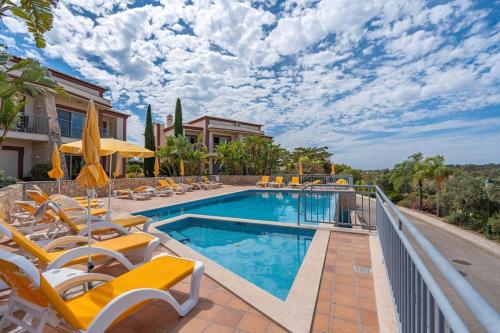 a swimming pool with chairs and a house at Vale Da Pinta Golf Resort in Carvoeiro